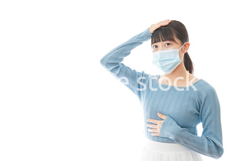 体調不良で苦しむマスクを付けた若い女性