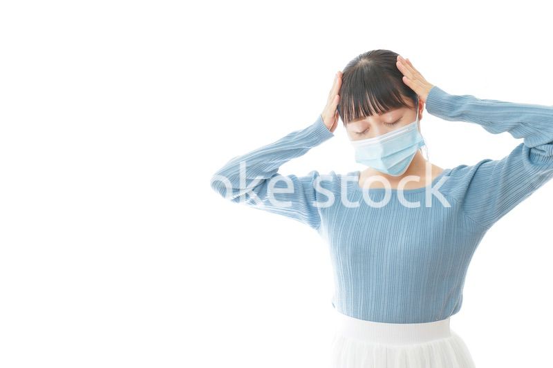 体調不良で苦しむマスクを付けた若い女性