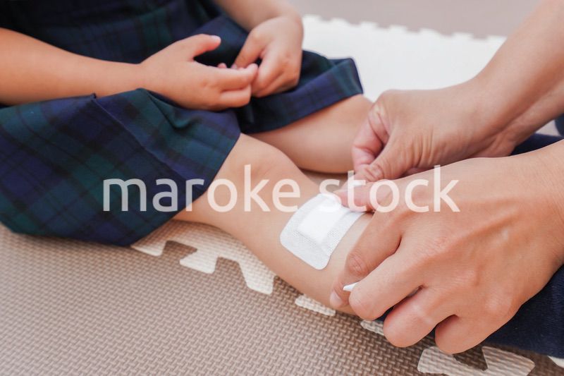 子供の怪我の手当をする保育士