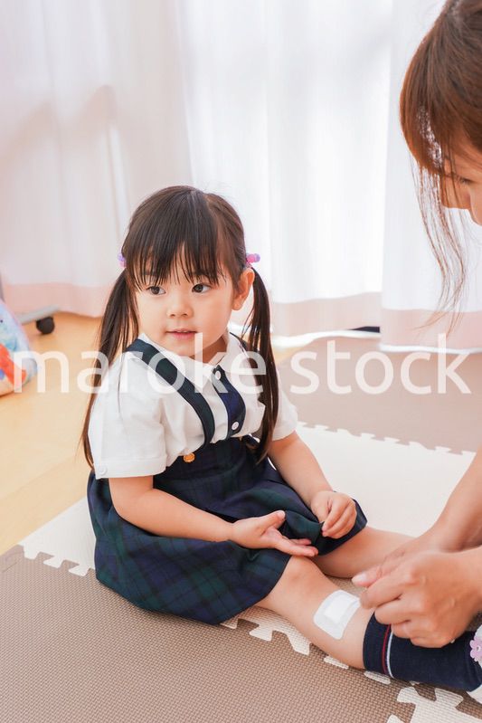 子供の怪我の手当をする保育士