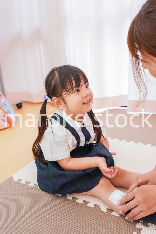 子供の怪我の手当をする保育士