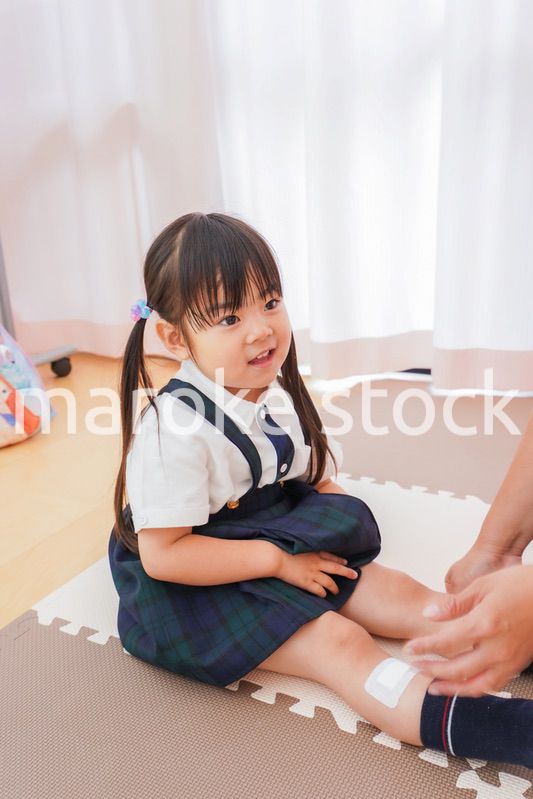 子供の怪我の手当をする保育士