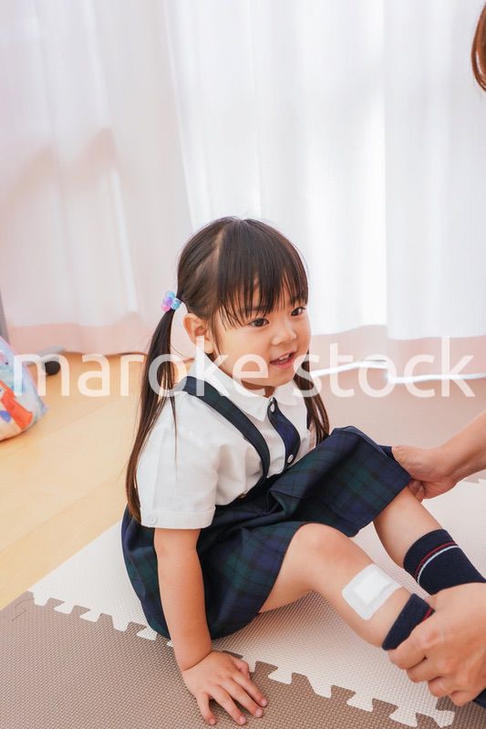 子供の怪我の手当をする保育士