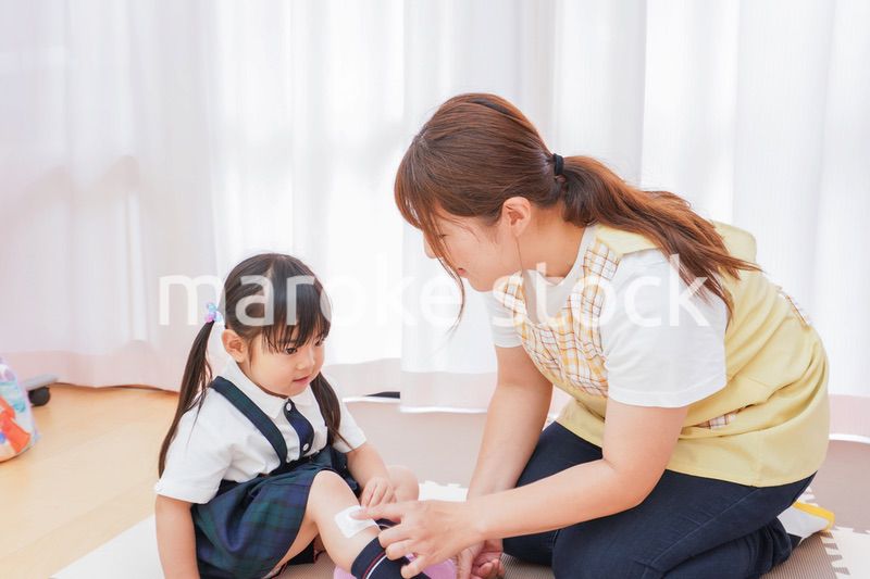 子供の怪我の手当をする保育士