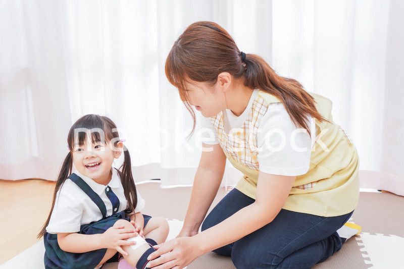 子供の怪我の手当をする保育士