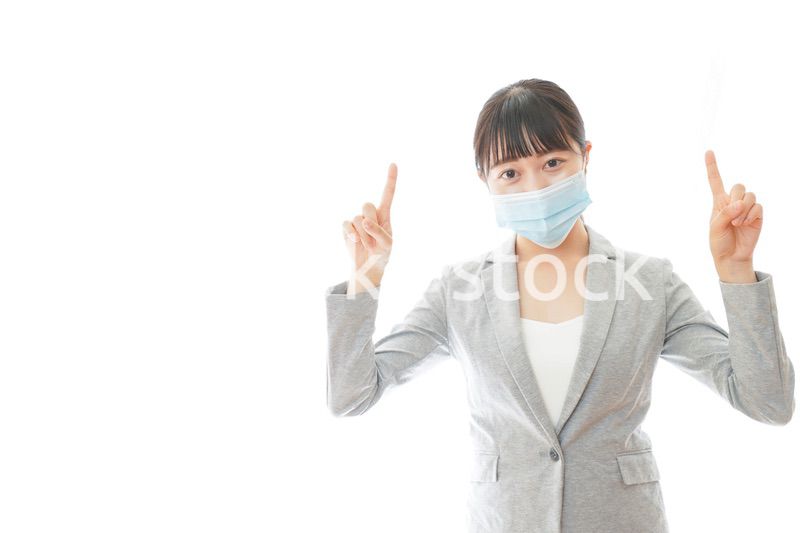 マスクをして指をさす若いビジネスパーソン