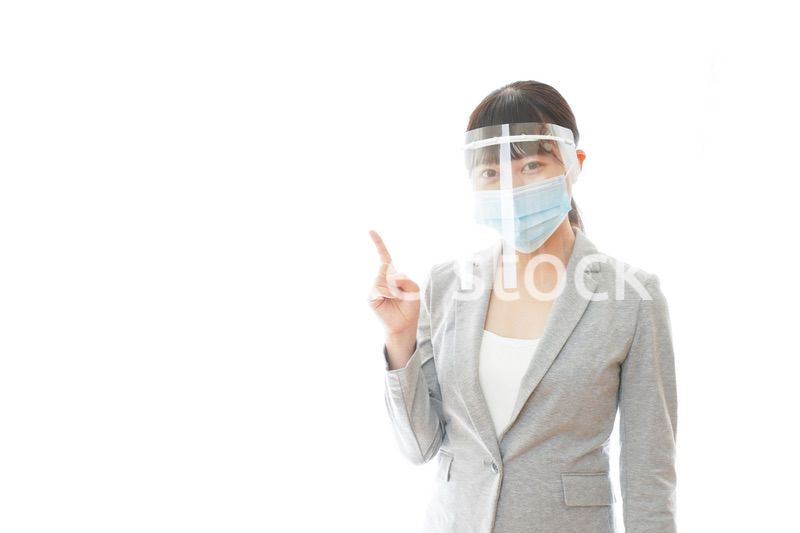 フェイスシールドをしてポイントを指差す若いビジネスウーマン