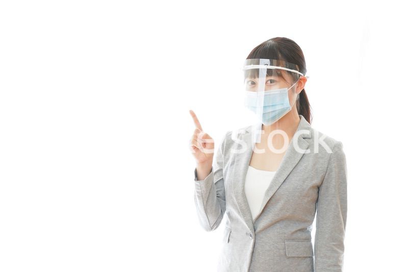 フェイスシールドをしてポイントを指差す若いビジネスウーマン