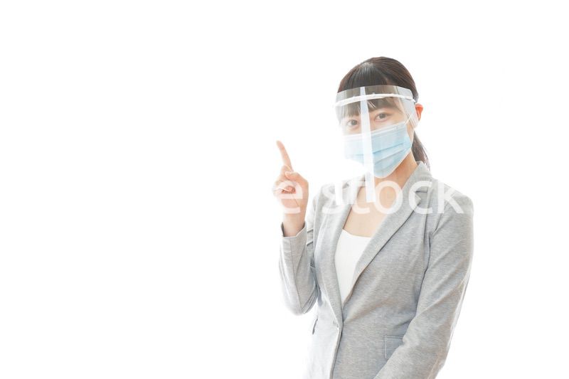 フェイスシールドをしてポイントを指差す若いビジネスウーマン