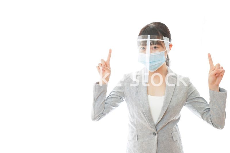 フェイスシールドをしてポイントを指差す若いビジネスウーマン