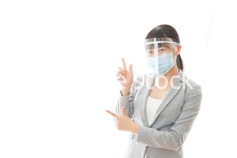 フェイスシールドをしてポイントを指差す若いビジネスウーマン