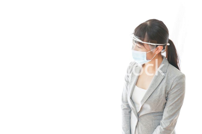 フェイスシールドを装着して接客をするビジネスウーマン