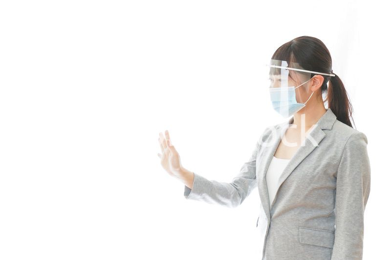 フェイスシールドを装着して接客をするビジネスウーマン