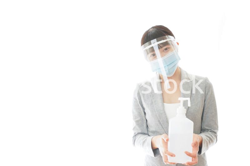 アルコール消毒液を持つフェイスシールドをしたビジネスウーマン