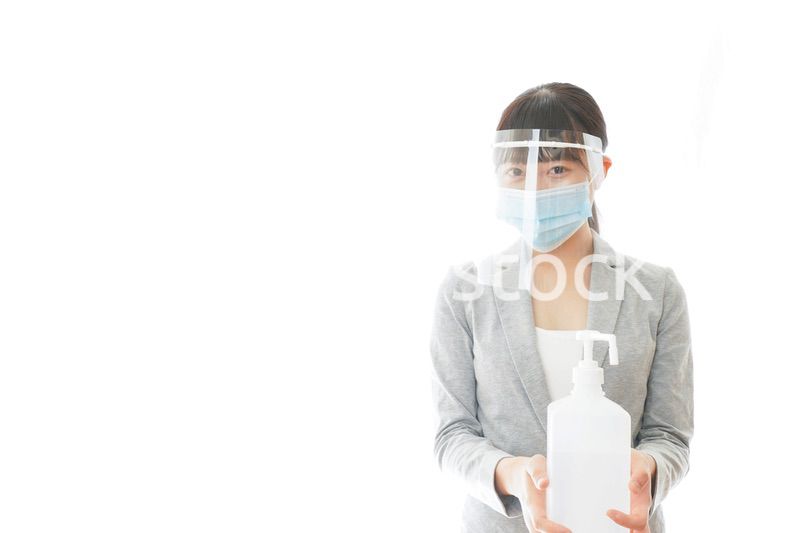 アルコール消毒液を持つフェイスシールドをしたビジネスウーマン