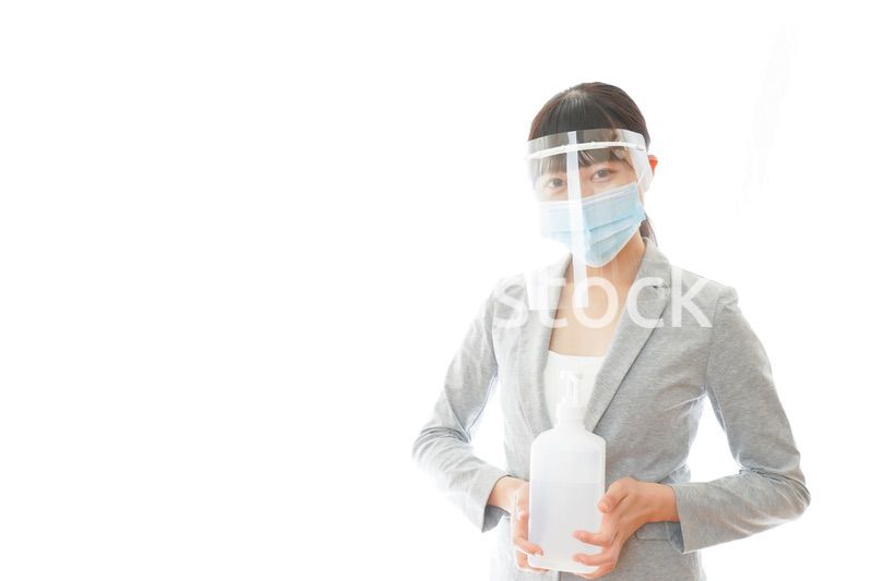 アルコール消毒液を持つフェイスシールドをしたビジネスウーマン