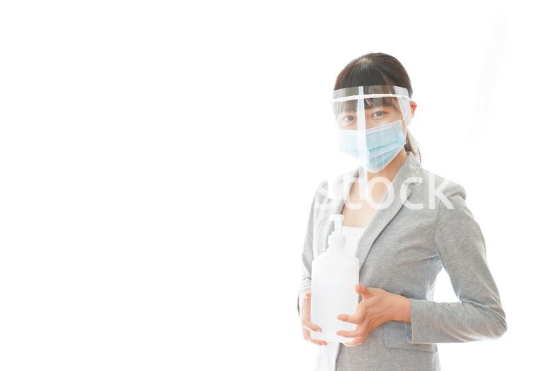 アルコール消毒液を持つフェイスシールドをしたビジネスウーマン