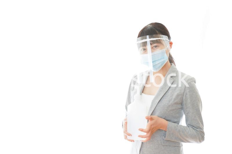 アルコール消毒液を持つフェイスシールドをしたビジネスウーマン