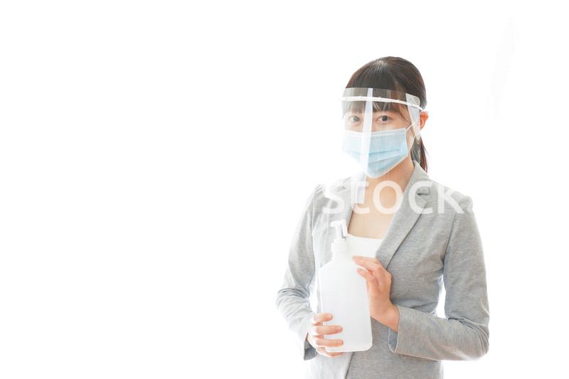 アルコール消毒液を持つフェイスシールドをしたビジネスウーマン