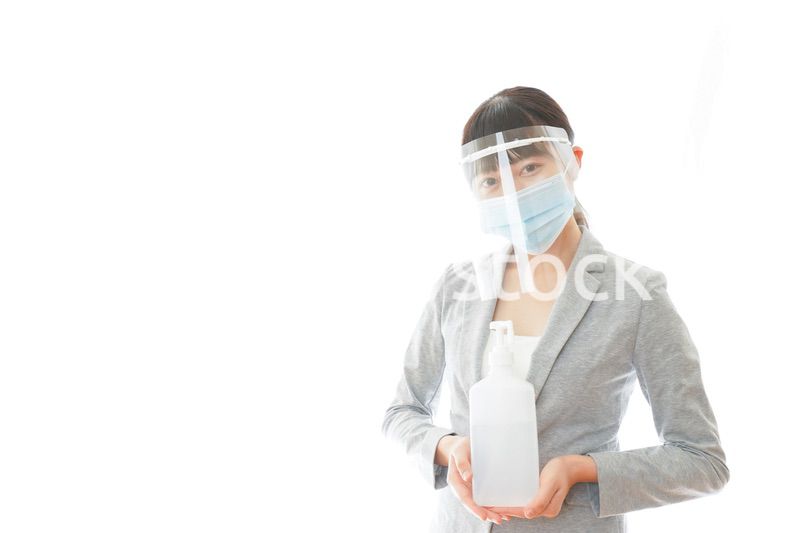 アルコール消毒液を持つフェイスシールドをしたビジネスウーマン