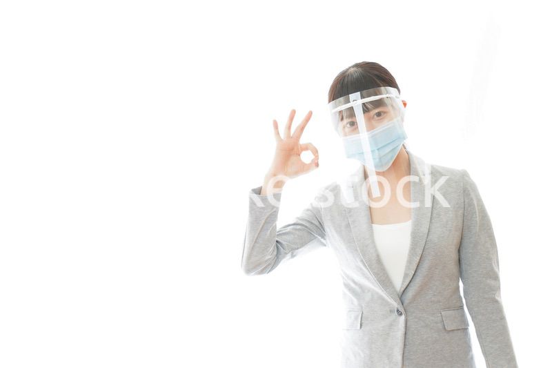 OKサインをするフェイスシールドを装着したビジネスウーマン