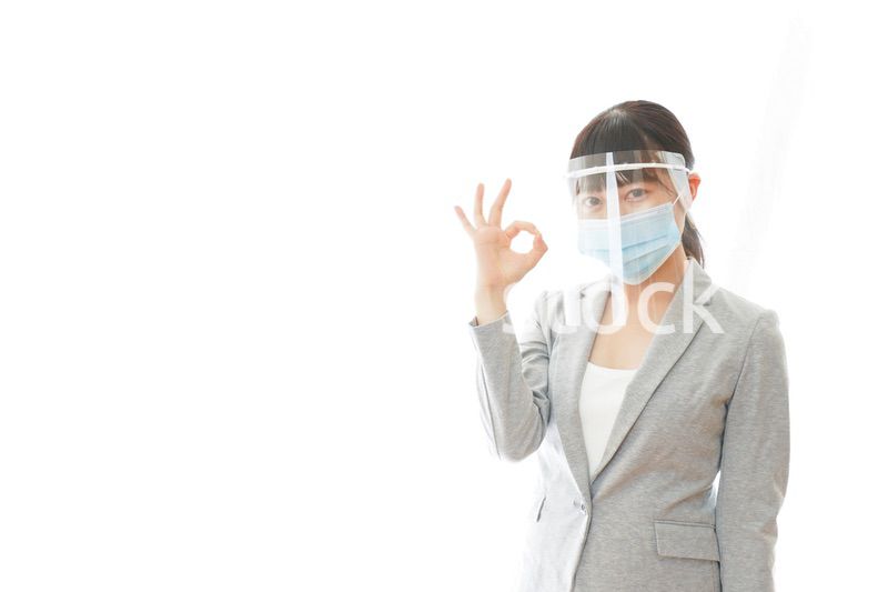 OKサインをするフェイスシールドを装着したビジネスウーマン