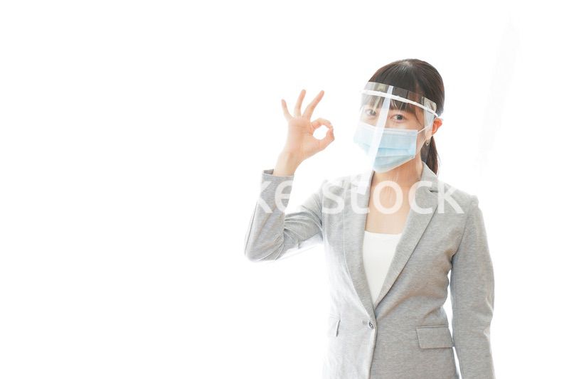 OKサインをするフェイスシールドを装着したビジネスウーマン