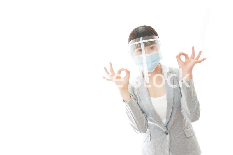 OKサインをするフェイスシールドを装着したビジネスウーマン