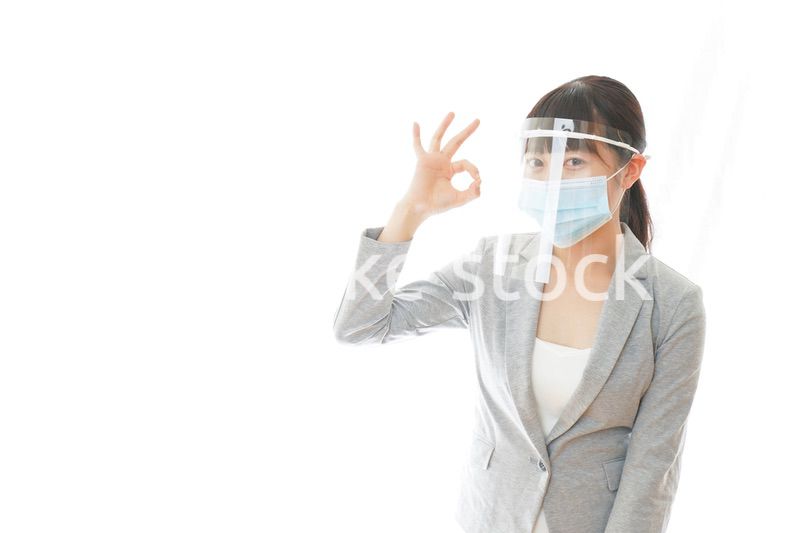 OKサインをするフェイスシールドを装着したビジネスウーマン