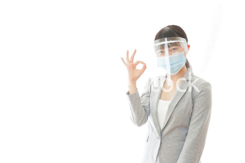 OKサインをするフェイスシールドを装着したビジネスウーマン