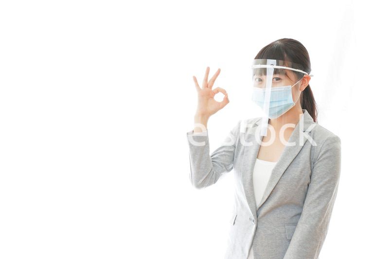 OKサインをするフェイスシールドを装着したビジネスウーマン