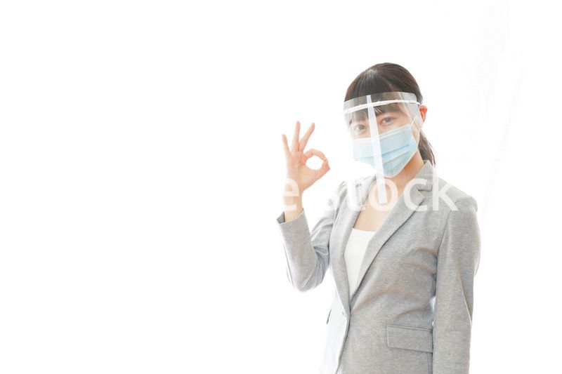 OKサインをするフェイスシールドを装着したビジネスウーマン