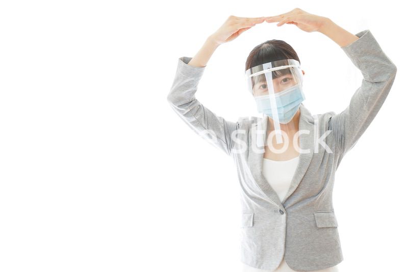 丸サインをするフェイスシールドを装着したビジネスウーマン