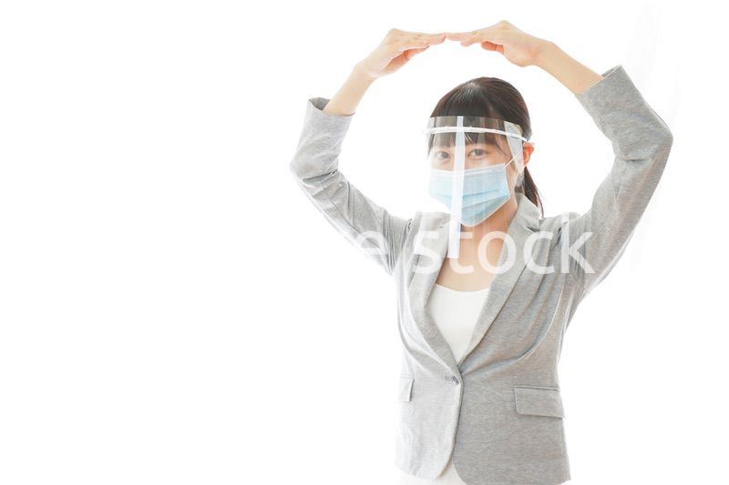 丸サインをするフェイスシールドを装着したビジネスウーマン