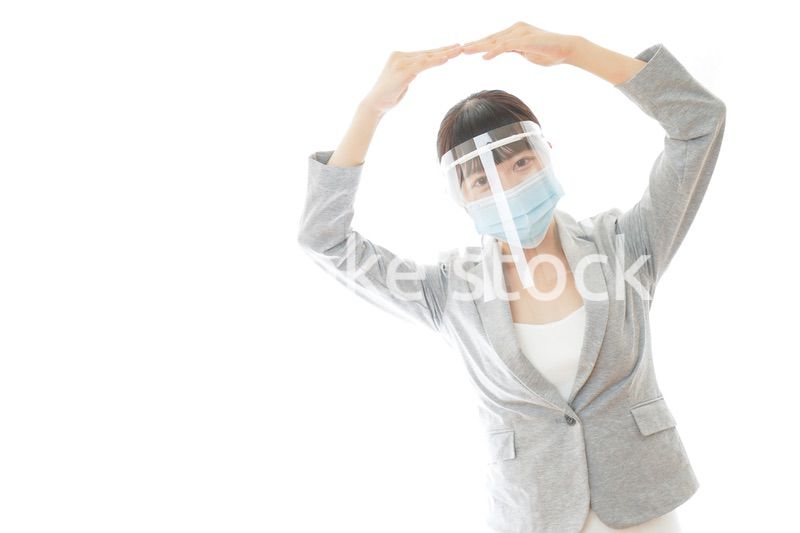 丸サインをするフェイスシールドを装着したビジネスウーマン