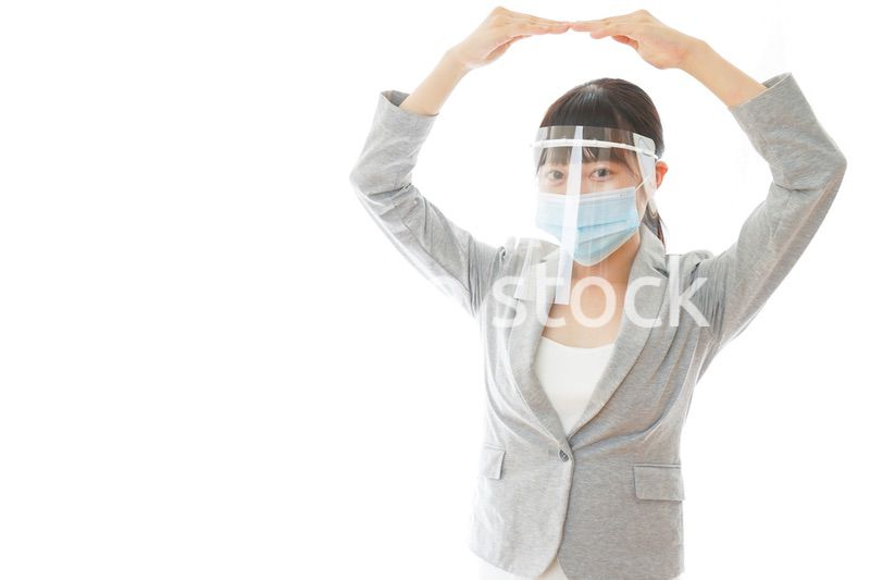 丸サインをするフェイスシールドを装着したビジネスウーマン