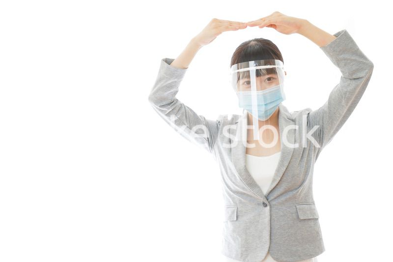 丸サインをするフェイスシールドを装着したビジネスウーマン