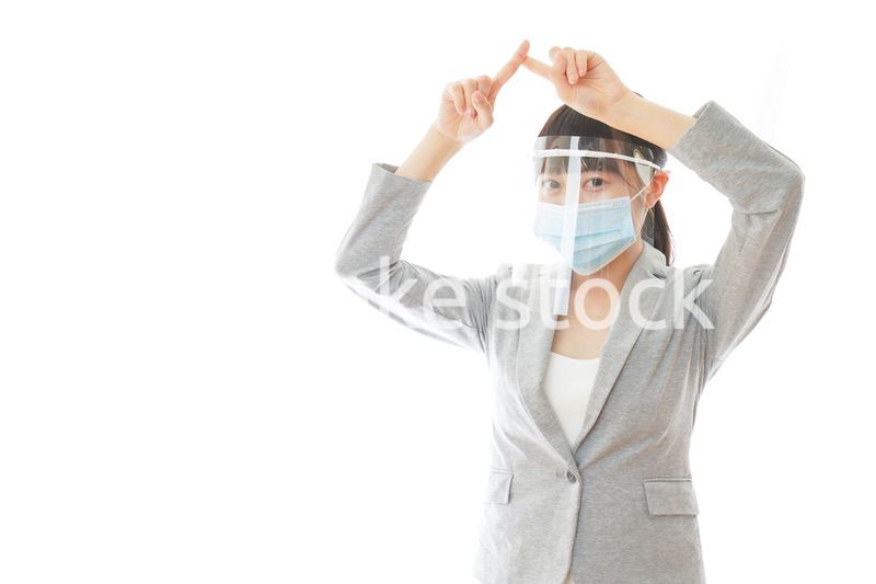 バツサインをするフェイスシールドを装着したビジネスウーマン