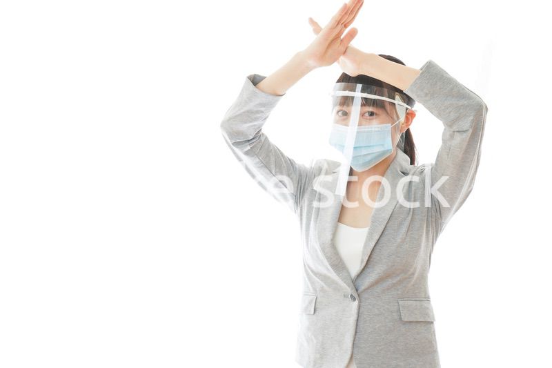 バツサインをするフェイスシールドを装着したビジネスウーマン