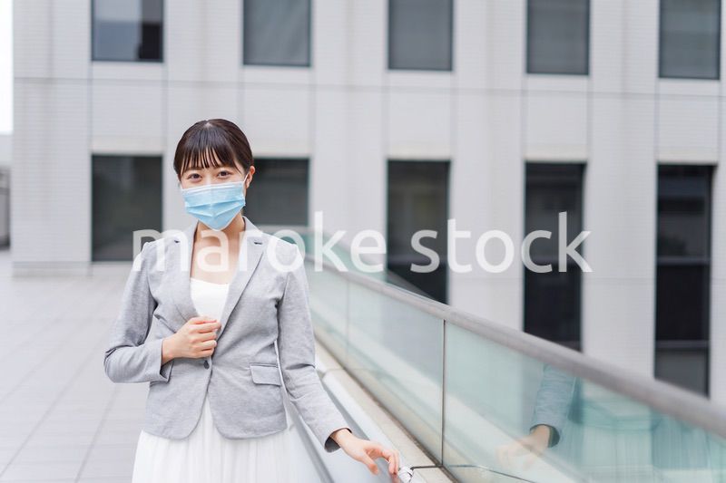 マスクをしてビジネス街を歩く若いビジネスウーマン