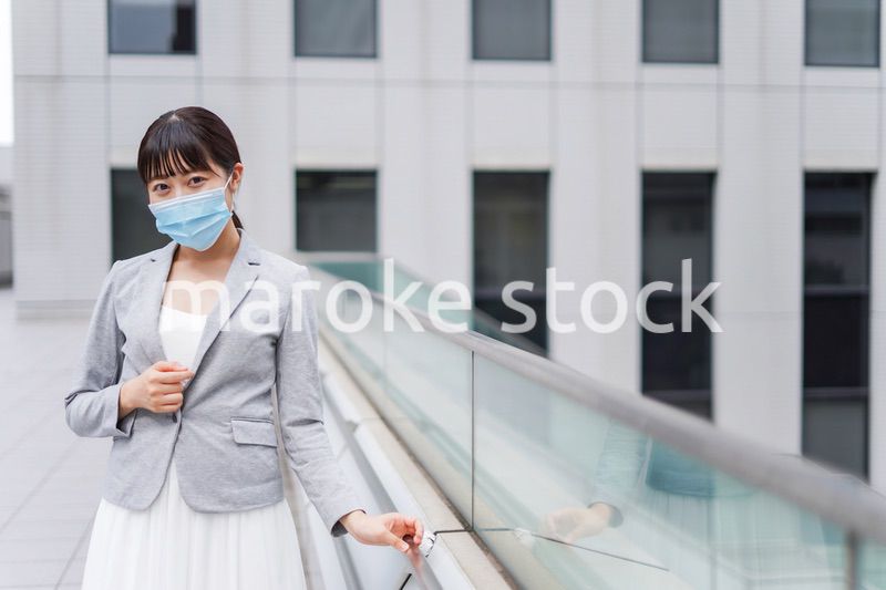 マスクをしてビジネス街を歩く若いビジネスウーマン