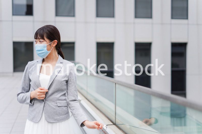マスクをしてビジネス街を歩く若いビジネスウーマン