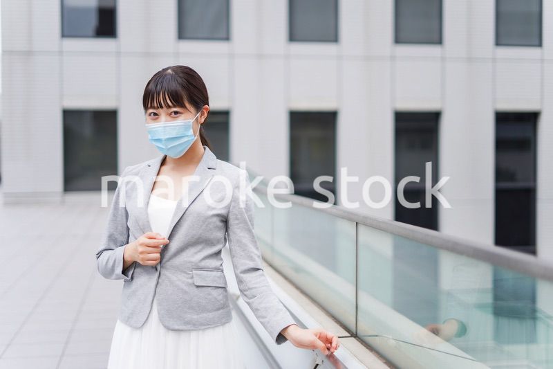 マスクをしてビジネス街を歩く若いビジネスウーマン