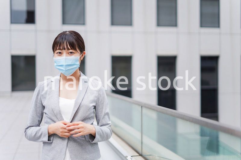 マスクをしてビジネス街を歩く若いビジネスウーマン