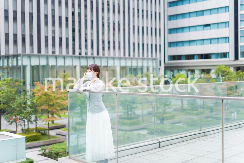 マスクをしてビジネス街を歩く若いビジネスウーマン