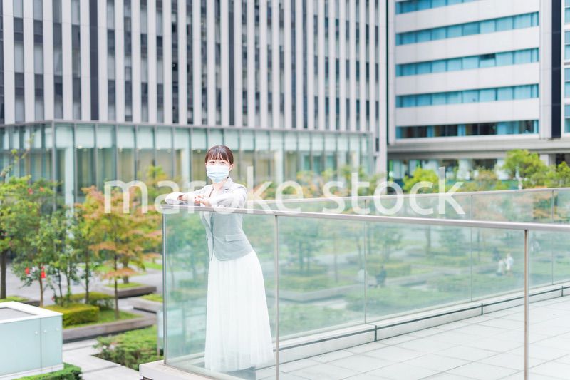 マスクをしてビジネス街を歩く若いビジネスウーマン