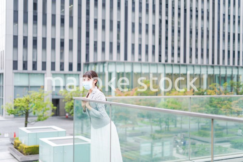 マスクをしてビジネス街を歩く若いビジネスウーマン