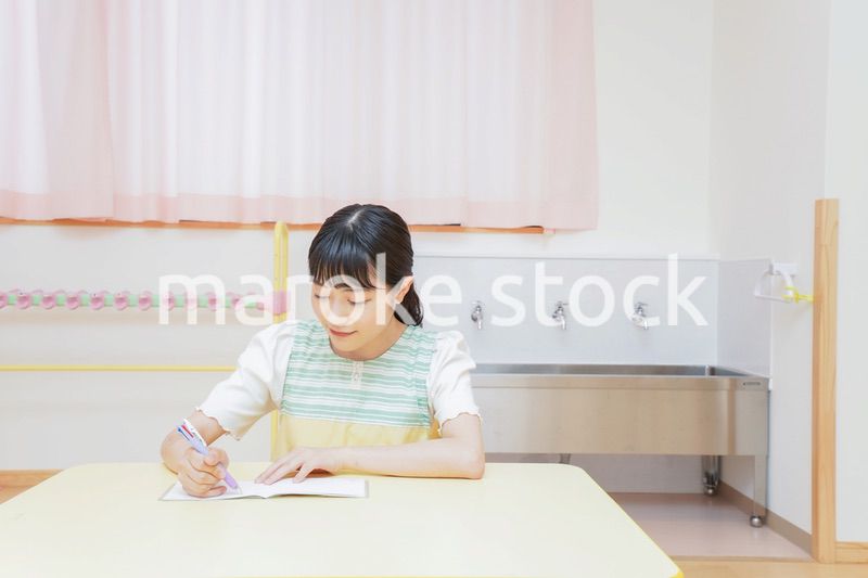 事務作業をする若い幼稚園教諭