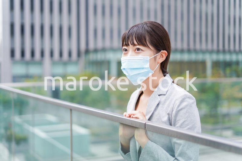 マスクをして外で休憩をする若いビジネスウーマン