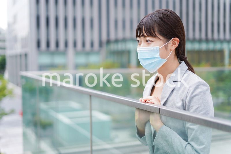 マスクをして外で休憩をする若いビジネスウーマン